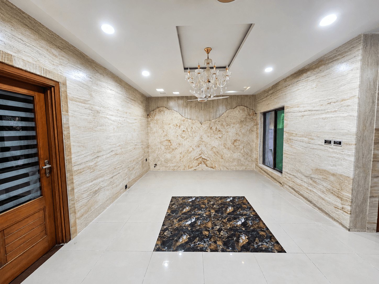 Living room feature wall in organic-cut travertine slab with a butterfly pattern beneath a chandelier