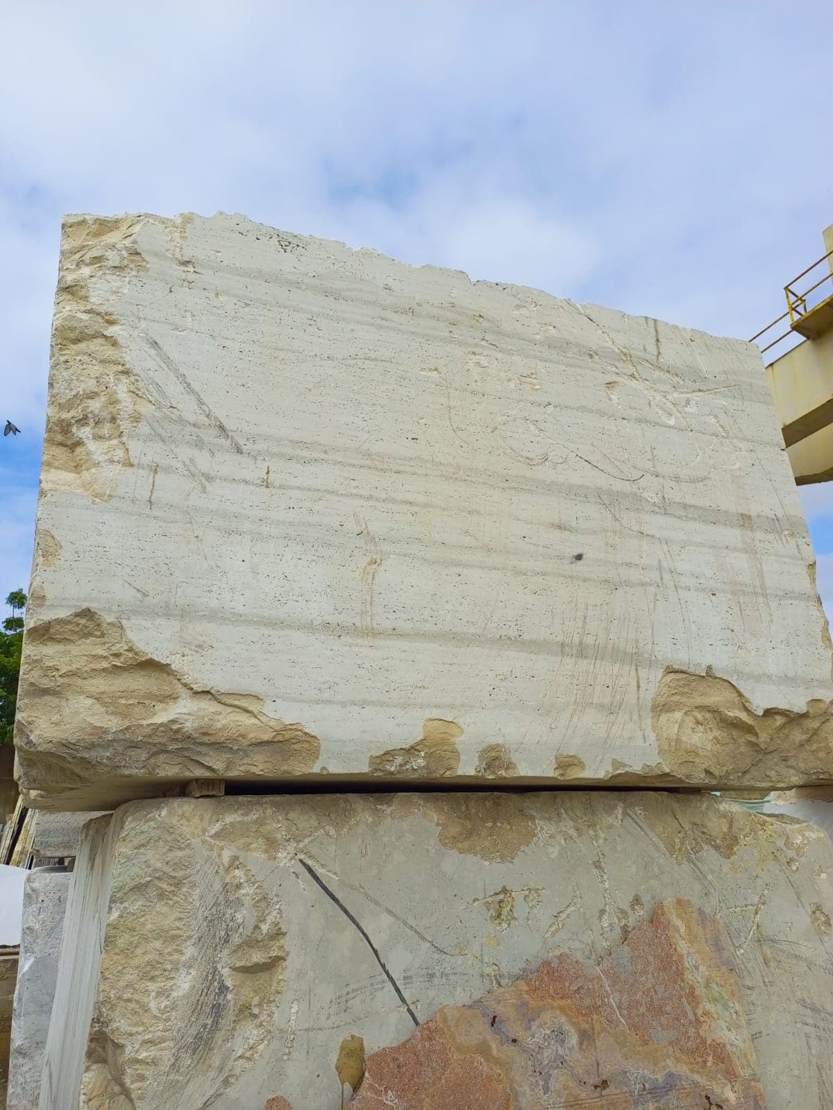 A massive raw travertine block freshly cut at the quarry face, stacked and ready for transport